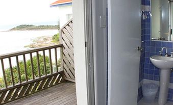 a bathroom with a toilet , sink , and shower , as well as a balcony overlooking the ocean at Pacific Hotel Yamba