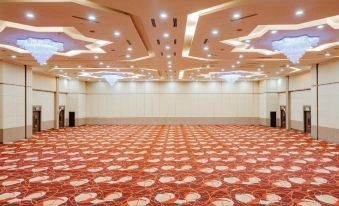 a large , empty conference room with high ceilings and orange carpet , illuminated by ceiling lights at Raia Hotel & Convention Centre Alor Setar