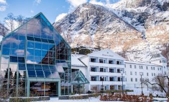 a modern building with a large glass window is surrounded by snow - covered mountains in the background at Fretheim Hotel