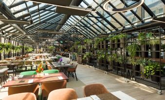 a large , open dining room with multiple tables and chairs arranged for a group of people to enjoy a meal together at NH Amsterdam Schiphol Airport