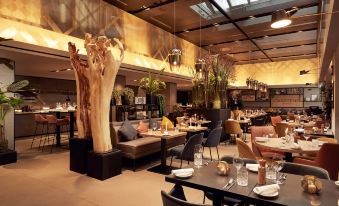 a modern restaurant with wooden tables , chairs , and a large tree in the middle of the dining area at Park Plaza Victoria Amsterdam