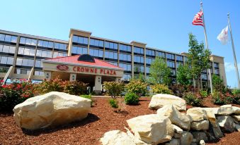 a large hotel building with a red roof , surrounded by rocks and greenery , under a clear blue sky at Crowne Plaza Cleveland Airport
