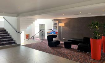 a modern living room with black furniture , including a couch and chairs , on a carpeted floor at Holiday Inn LILLE - OUEST ENGLOS by IHG
