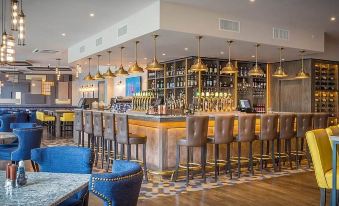 a modern restaurant with a bar area , where several people are seated and enjoying their meals at Harbour Hotel