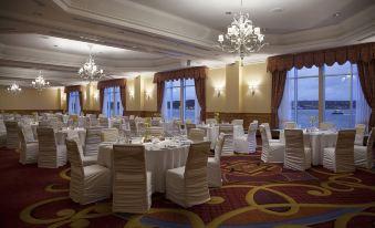 a large banquet hall filled with white chairs and tables , ready for a formal event at Halifax Marriott Harbourfront Hotel