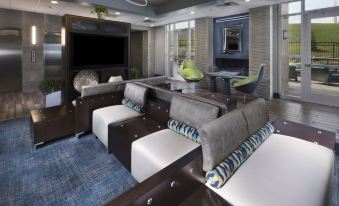 a modern living room with multiple couches and chairs arranged around a coffee table , creating a cozy atmosphere at Holiday Inn & Suites Arden - Asheville Airport