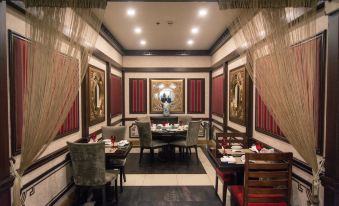 a dining room with a round table surrounded by chairs , and a chandelier hanging from the ceiling at Islamabad Marriott Hotel