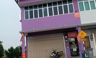 a purple building with a motorcycle parked in front and chinese signs on the side at Muar Golden Horse Hotel