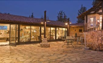 a courtyard with a stone building and several tables and chairs set up for outdoor dining at Like Home Gedera