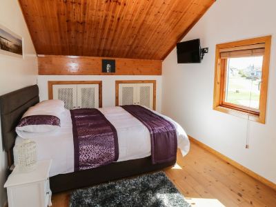 a cozy bedroom with wooden ceiling , white walls , and a large bed decorated with purple bedding at Moon Face