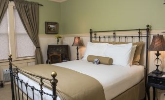 a bed with white and beige linens is situated in a room with green walls at Chamberlin Inn
