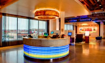 a modern hotel lobby with a large circular reception desk and a unique circular light fixture at Aloft Leawood-Overland Park