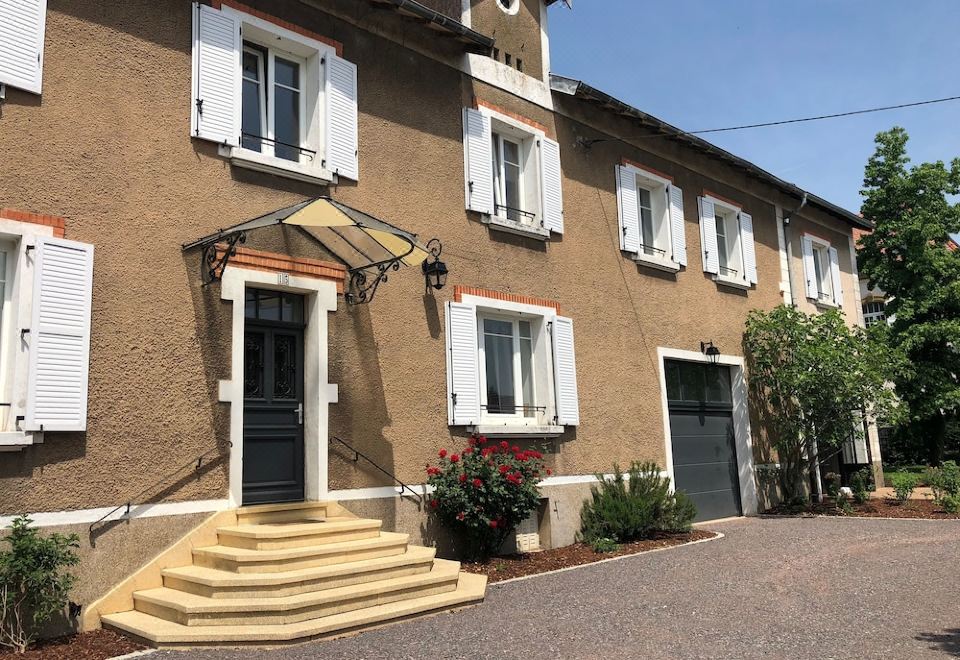 a brown building with white shutters and a staircase leading up to the front door at La Parenthèse