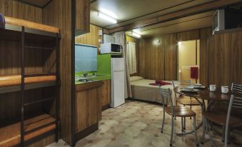 a small , cozy hotel room with wooden walls , a kitchenette , and a bunk bed , as well as a dining table and chairs at Cairns Sunland Leisure Park