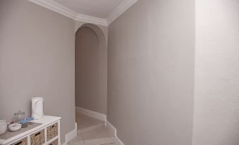 a narrow hallway with a white tile floor and beige walls , leading to a staircase at Bella Vista