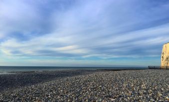 a vast , rocky beach with a clear blue sky and distant sea on a cloudy day at Bellevue Beaurivage