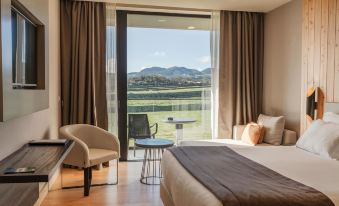 a bedroom with a large window overlooking a lake , providing a scenic view of the area at Pedras do Mar Resort & Spa