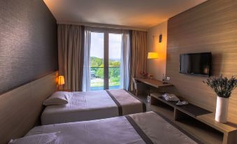 a hotel room with two beds , a tv , and a window overlooking a beautiful view at Quality Hotel San Martino