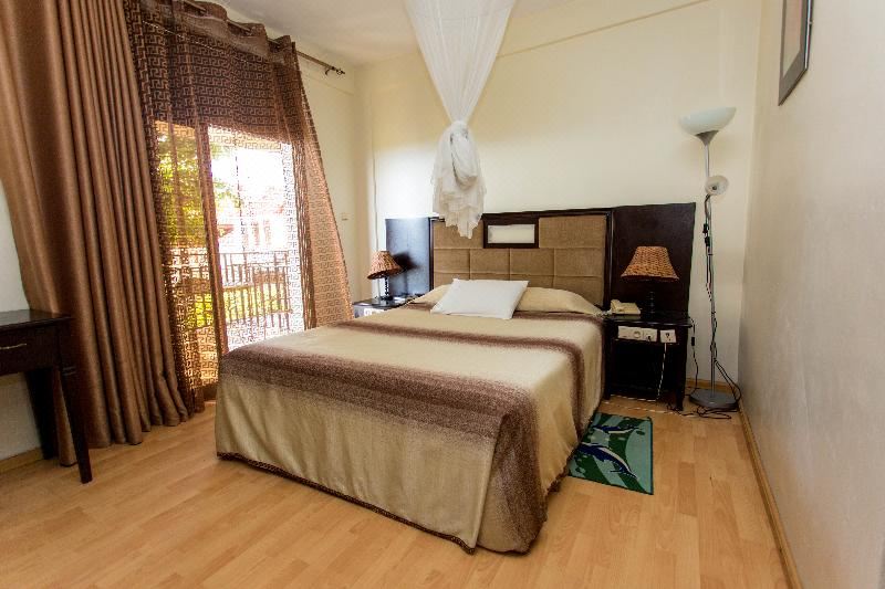 a bedroom with a large bed , wooden floors , and a window overlooking a balcony with a view of the city at Belvedere Hotel