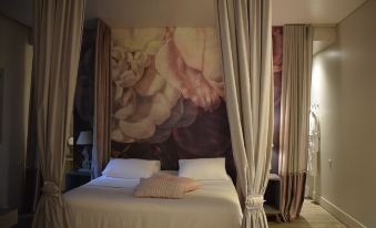 a bed with a white comforter and pillows is shown in front of a large floral mural at Mikelina Boutique Hotel