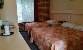 a hotel room with two beds , one on the left and one on the right side of the room at The Mullum Motel