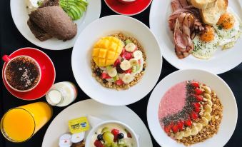 a variety of breakfast foods , including oatmeal , fruit , bread , and meat , arranged on a table at Quest Mawson Lakes