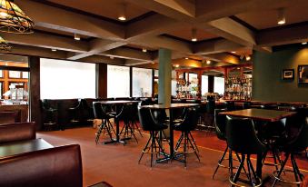 a bar with several black stools and chairs , as well as several tables and chairs at The Inn at Silvercreek