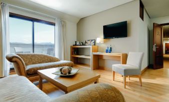 a cozy living room with a large window , wooden floor , and furniture including a couch , coffee table , and bookshelf at Hesperia Vigo