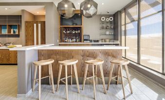 a modern kitchen with a wooden bar , four bar stools , and a variety of bottles on the counter at SpringHill Suites Dayton Vandalia