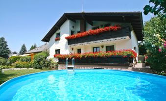 a large house with a swimming pool in its backyard , surrounded by lush greenery and flowers at Anita