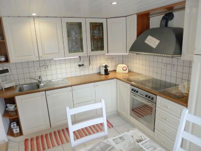 a clean and well - organized kitchen with white cabinets , a stove , oven , sink , and dining table at Marilyn Visperterminen