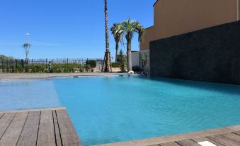 a large swimming pool with a wooden deck and palm trees in the background , under a clear blue sky at Balnea