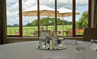 a table with two glasses of water and a menu is set up in front of a large window at Best Western Preston Garstang Country Hotel and Golf Club