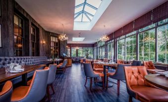 a large , well - lit restaurant with multiple dining tables and chairs , as well as an open - air seating area at Dunkeld House Hotel