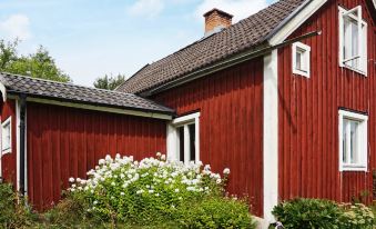 a red wooden house surrounded by a lush green garden , with a mailbox in the yard at Vadstena