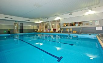 an indoor swimming pool with blue water , surrounded by white walls and a glass ceiling at Brooklands of Mornington