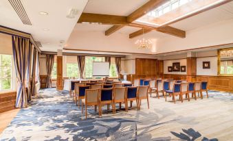 a large conference room with wooden chairs and a blue carpeted floor , set up for a meeting or event at Dunkeld House Hotel