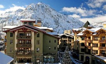 a snowy mountain landscape with a group of buildings and a christmas tree in the foreground at The Village at Palisades Tahoe