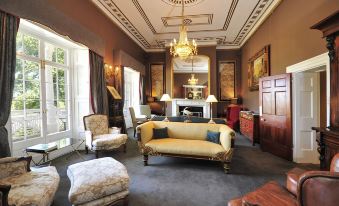 a large , elegant living room with a piano in the center , surrounded by chairs and couches at Quamby Estate