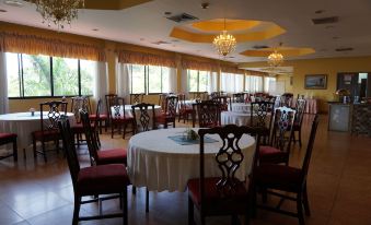 a large dining room with numerous tables and chairs arranged for a group of people to enjoy a meal together at Ambassador Hotel