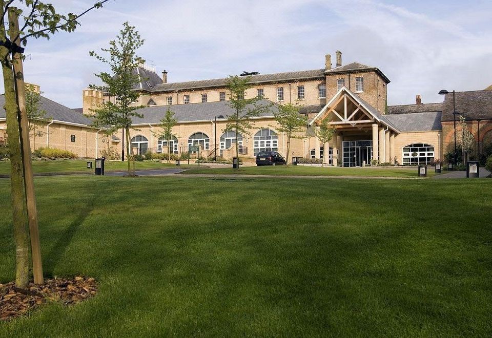 a large building with a green lawn in front of it and cars parked outside at De Vere Beaumont Estate