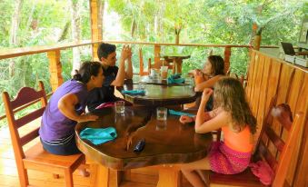 a group of people gathered around a dining table in a treehouse , enjoying a meal together at Drake Bay Getaway Resort by Sandglass