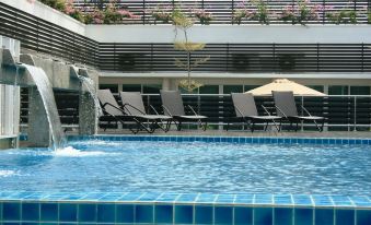 a swimming pool with lounge chairs and a waterfall feature , surrounded by a modern building with black lattice work and a balcony filled with flowers at Hotel Sfera