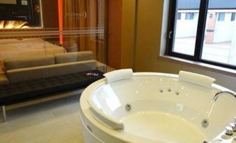 a modern bathroom with a large white bathtub and a red light in the background at Hotel Camelia