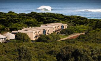 a resort surrounded by trees and the ocean , with a surfboard visible in the background at Margarets Beach Resort