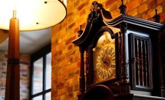 a large , ornate clock is displayed on a wooden cabinet in front of a brick wall at La Vista Hakodate Bay