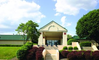 a brick building with a green roof , surrounded by trees and bushes , under a blue sky at Ramada by Wyndham Clarion