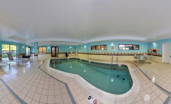 a large indoor swimming pool with a curved edge , surrounded by blue walls and white tiles at SpringHill Suites Pittsburgh Mills