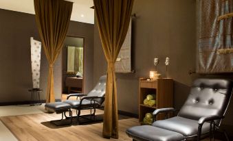 a modern spa room with wooden flooring , gray leather chairs , and large windows covered by gold curtains at Best Western Premier la Grande Hotel