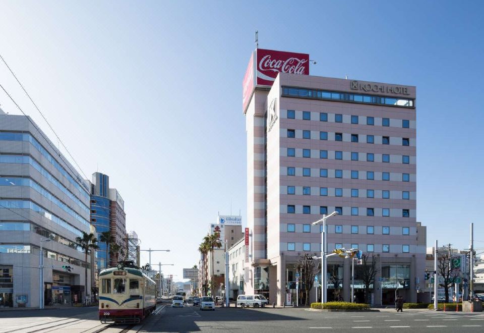 a city street with a tall building and a coca - cola sign on the side of the building at Kochi Hotel